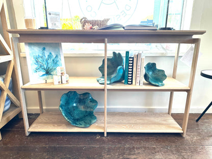 Image of midcentury white oak console in store window with decorations on it.